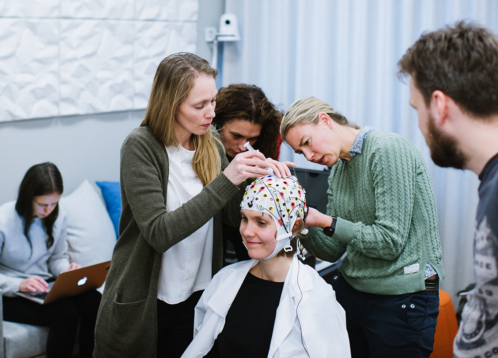 Three researchers in the lab preparing a participant for EEG
