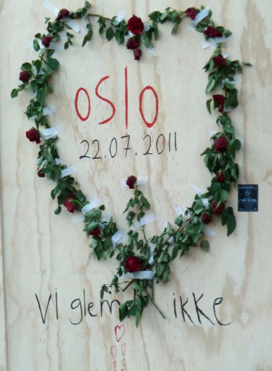 Roses pinned to a canvas in the shape of a heart with the text "Oslo 22.07.2011 - we don't forget"