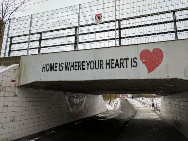 Teksten ?Home is where your heart is? st?r med svart skrift p? en bro. Et r?dt hjerte ved siden av. Foto.