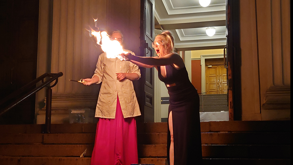 To festkledte studenter med flammer i henende p? trappa ved inngangen til Domus Bibliotheca 