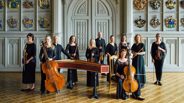 Orkesterbilde av Finnish Baroque Orchestra samlet rundt en cembalo i historisk sal