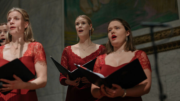 Tre sangere fra Solistkoret i r?de kjoler foran Edvard Munchs malerier i Aulaen