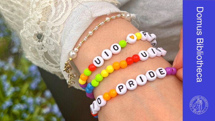 N?rbilde av h?nd med perlearmb?nd i ulike farger og bokstavperler med "UiO" og "Pride"