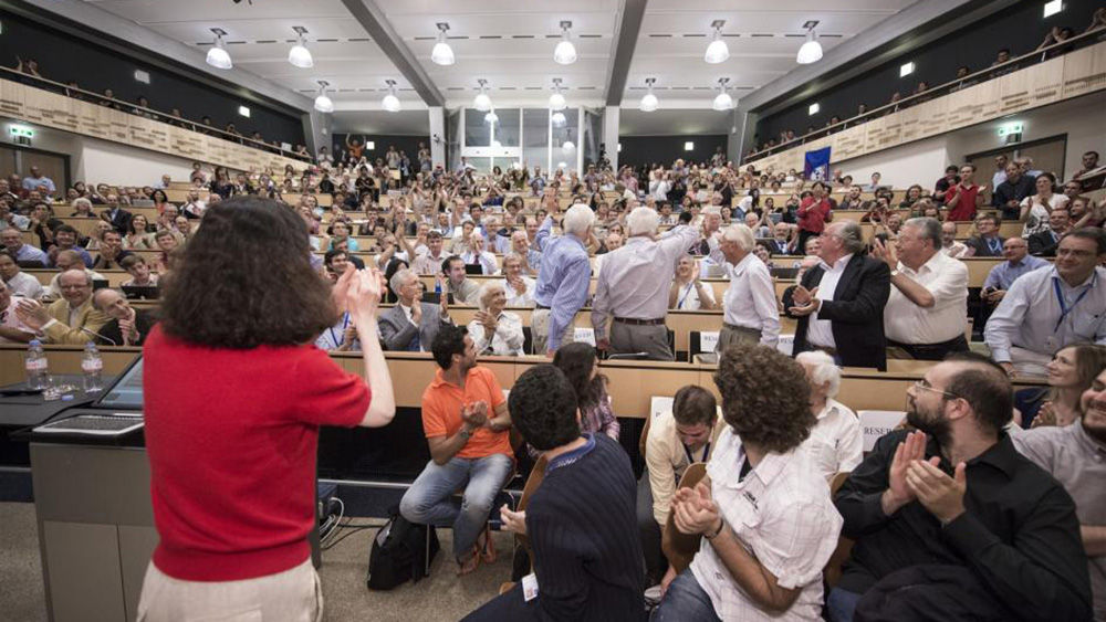 Bilde fra auditorium fullt av folk som feirer oppdagelsen av Higgspartikkelen