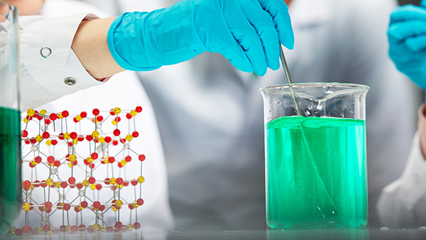 Hand mixing green liquid next to a molecule model