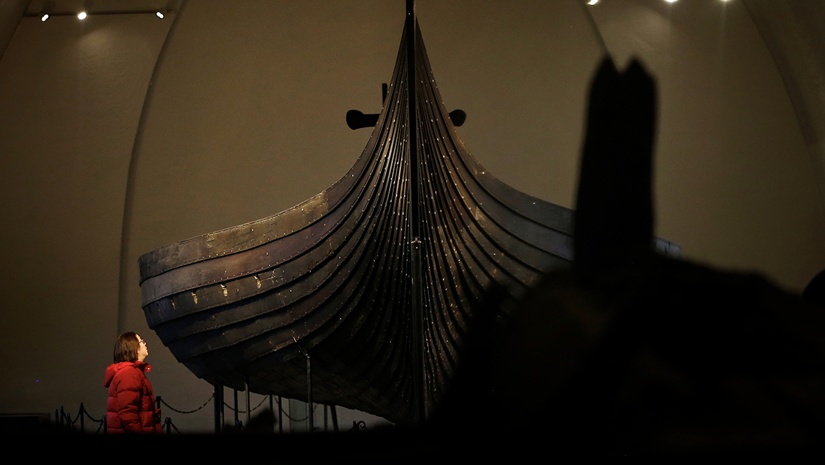 Kvinne beundrer vikingskipet Gokstad i Vikingskiphuset
