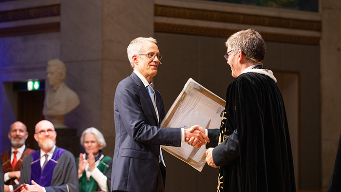 Researcher receives a diploma from Rector on stage