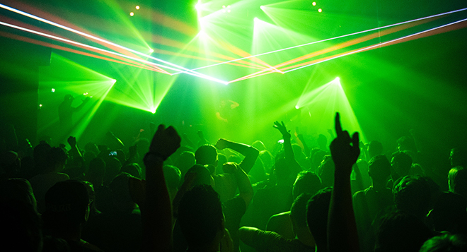 People dancing in a club with strong green light effects