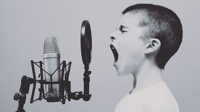 A black and white photo of a boy who screams inside a microphone