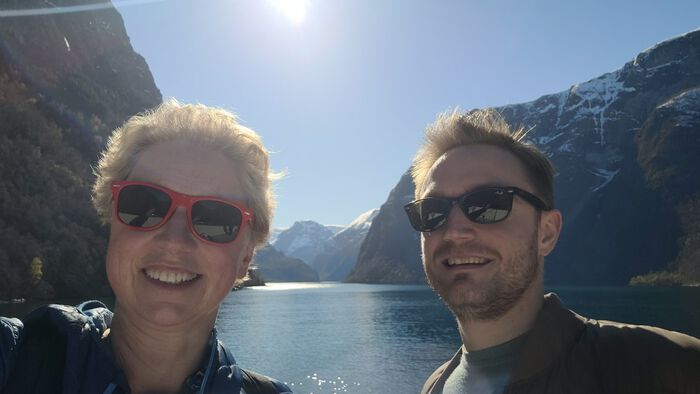 Caroline Palmer and Valentin Bgel in the foreground, a Norwegian fjord with snowy mountains and sunshine in the background.