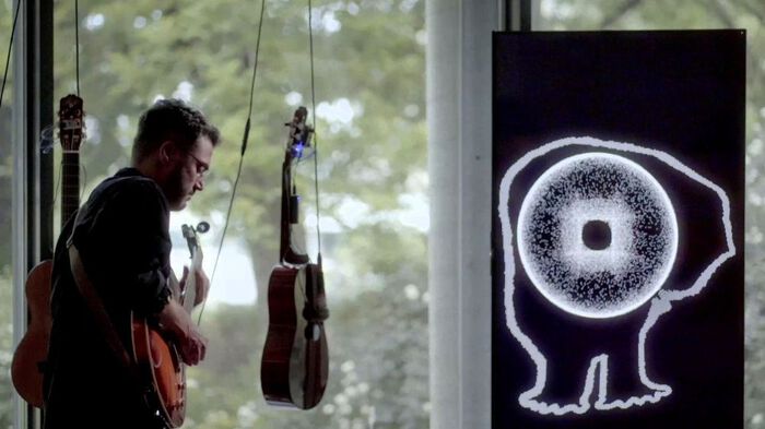 ?a?r? Erdem playing guitar in front of two suspended guitars