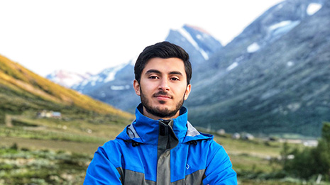 Portrettbilde ute av Ahmed med fjell og daler i bakgrunnen