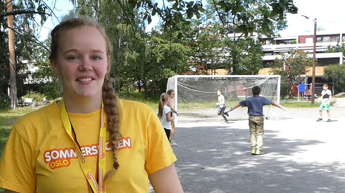 Bilde av blid Veronica i gul t-skjorte foran unger som er ute og spiller fotball