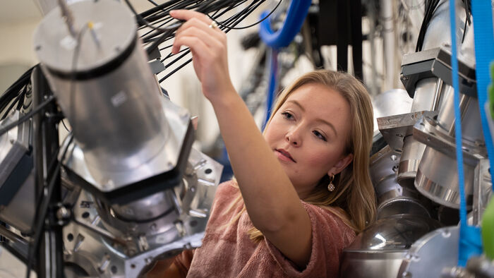 Kvinnelig student som stiler inn utstyr i syklotronlaboratoriet ved UiO