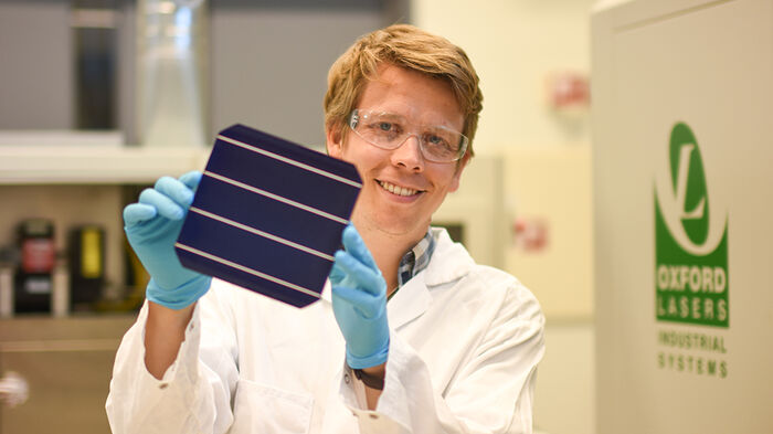 Halvard p? laben med verneutstyr. holder opp en solcelle. 