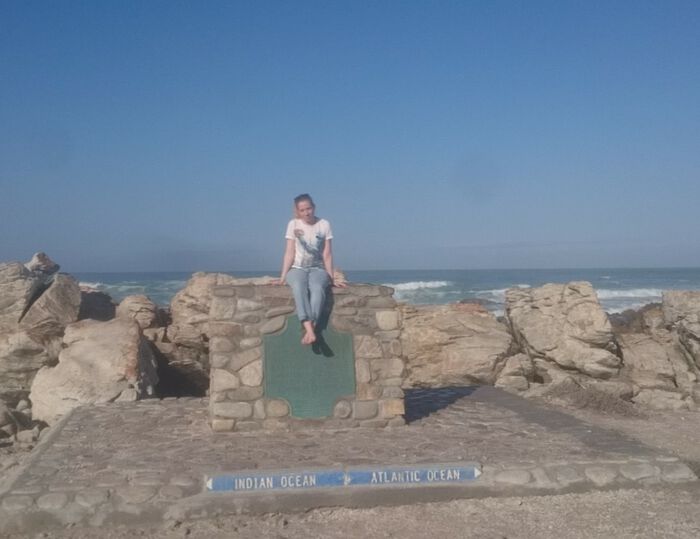 Jente som sitter p? en sten ved havet i Cape Town