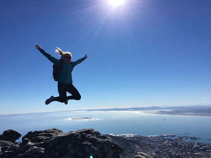 Jente som hopper p? toppen av et fjell med byen Cape Town i bakgrunnen