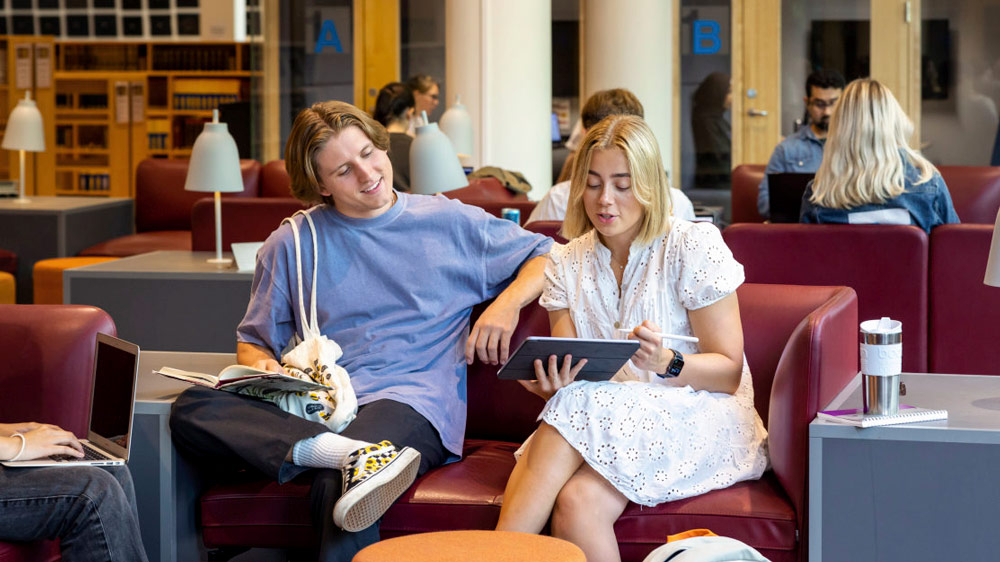 To UiO-studenter sitter i sofa og ser p? en iPad